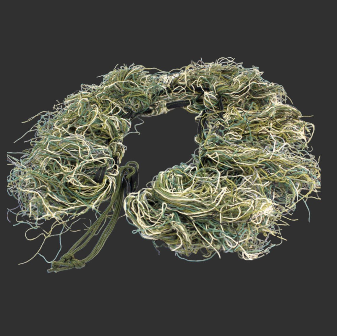 A StealthGuard Gun Cover by BlasterMasters, a coil of tangled green, tan, and white strings resembling camouflage, is placed against a dark gray background.