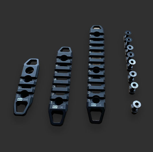 Three black metal brackets of varying lengths with labeled slots and associated small cylindrical components, ideal for firearm customization with BlasterMasters M-LOK Picatinny Rail Sections, are arranged on a dark background.